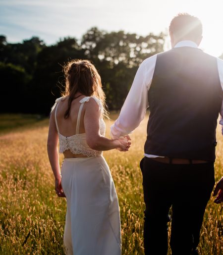 Happy married couple walking in field at Cuckoo Down Glamping in Exeter