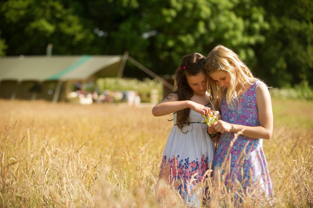2 girls playing outside a glamping safari tent in Devon