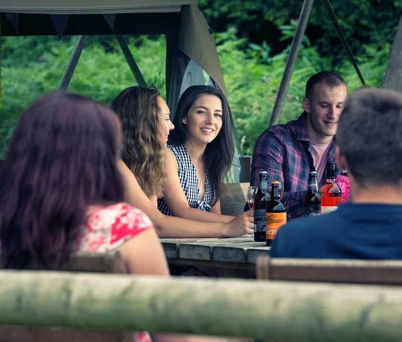 group of young people talking outside a glamping tent in devon