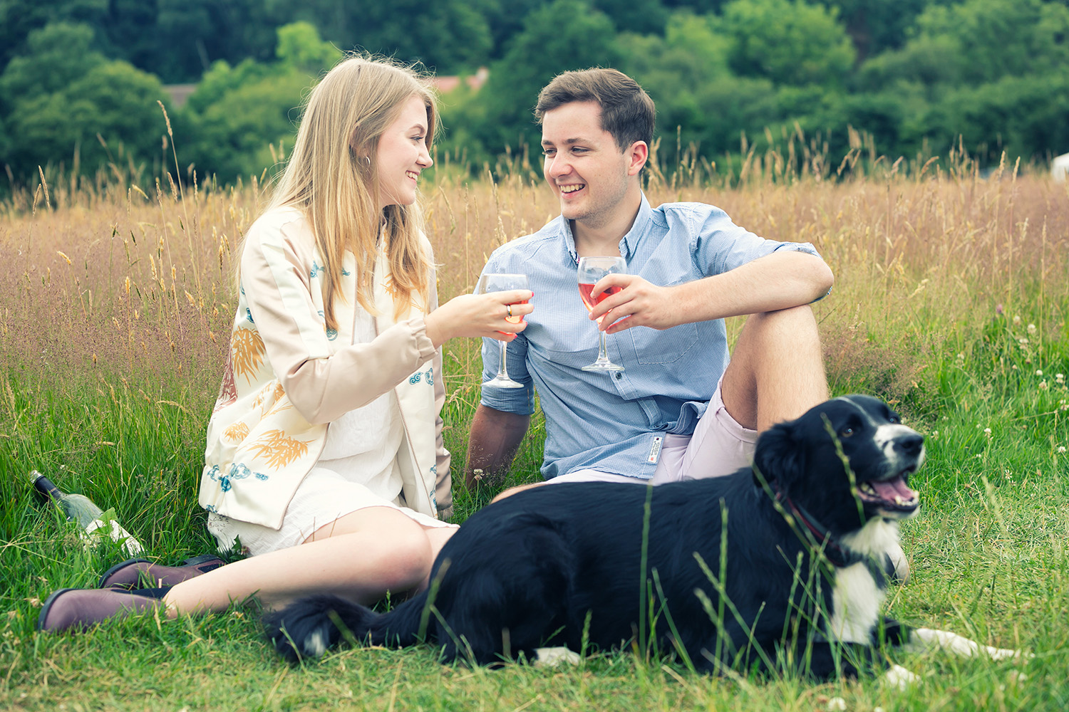 couple enjoying a drink together in a field whilst on holiday with their dog