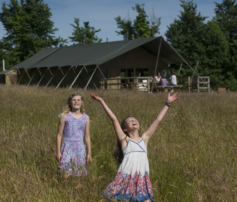 two girls playing outside their glamping lodge on holiday in Devon